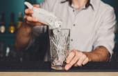 barman pouring ice into a cup